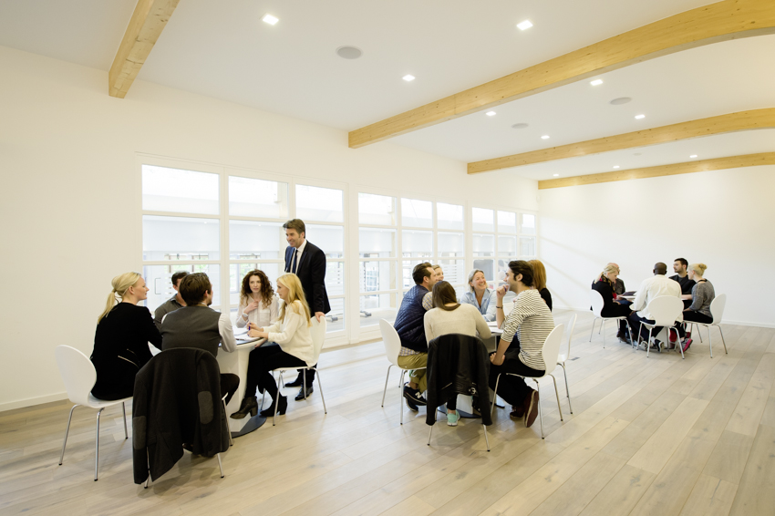 Menschen sitzen in Gruppen an Tischen in einem großen Raum in einem Fitnessstudio