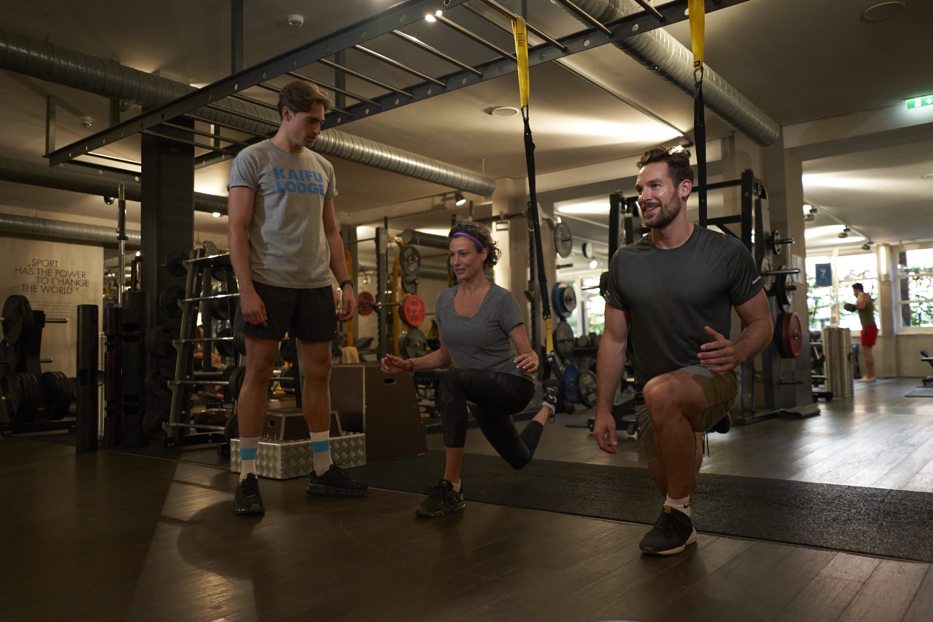 A trainer gives ndividual coaching and personal training to a man and a woman in the gym