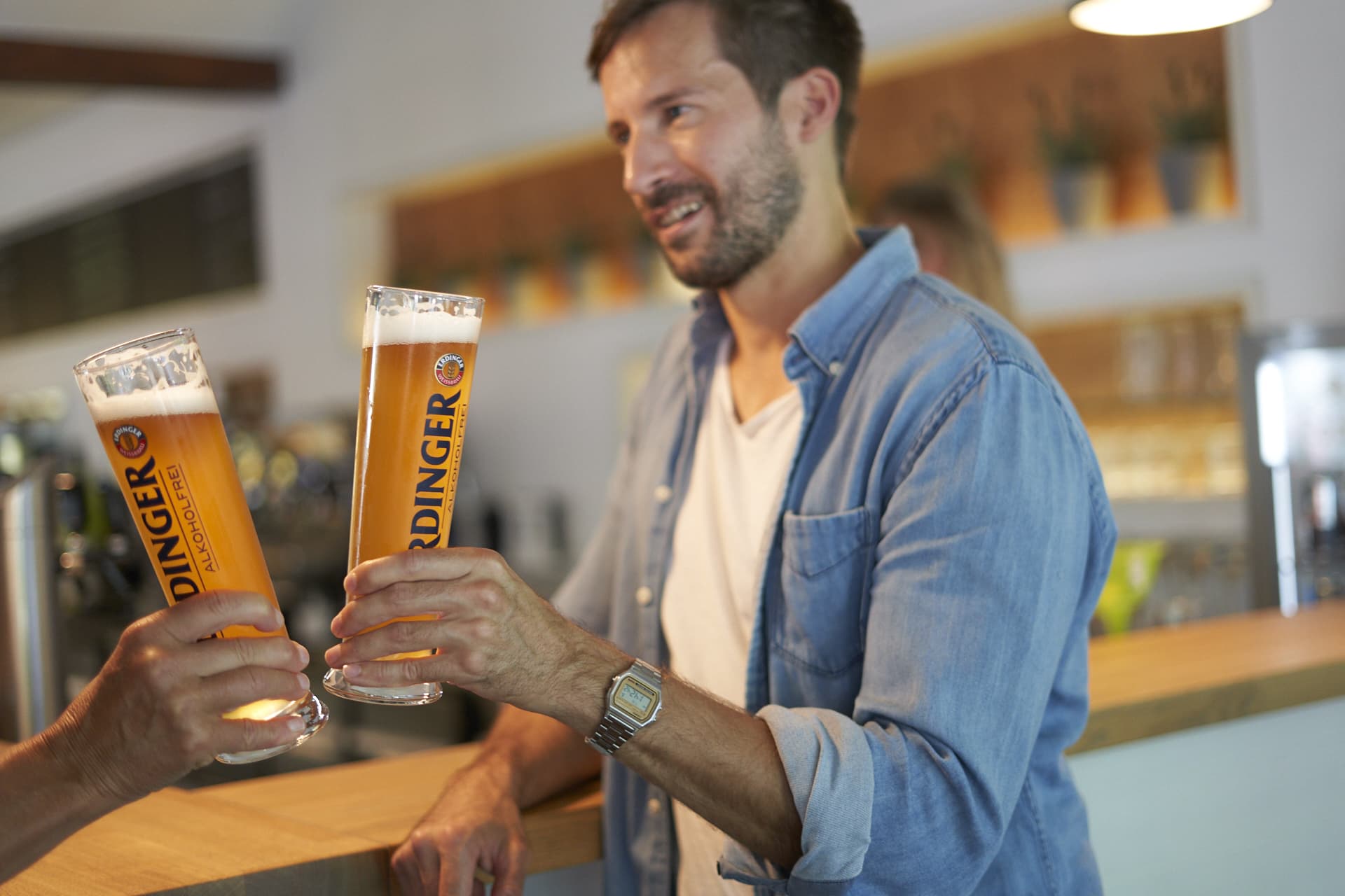 ein Mann stößt mit Bier an in einem Restaurant eines Fitnessstudios