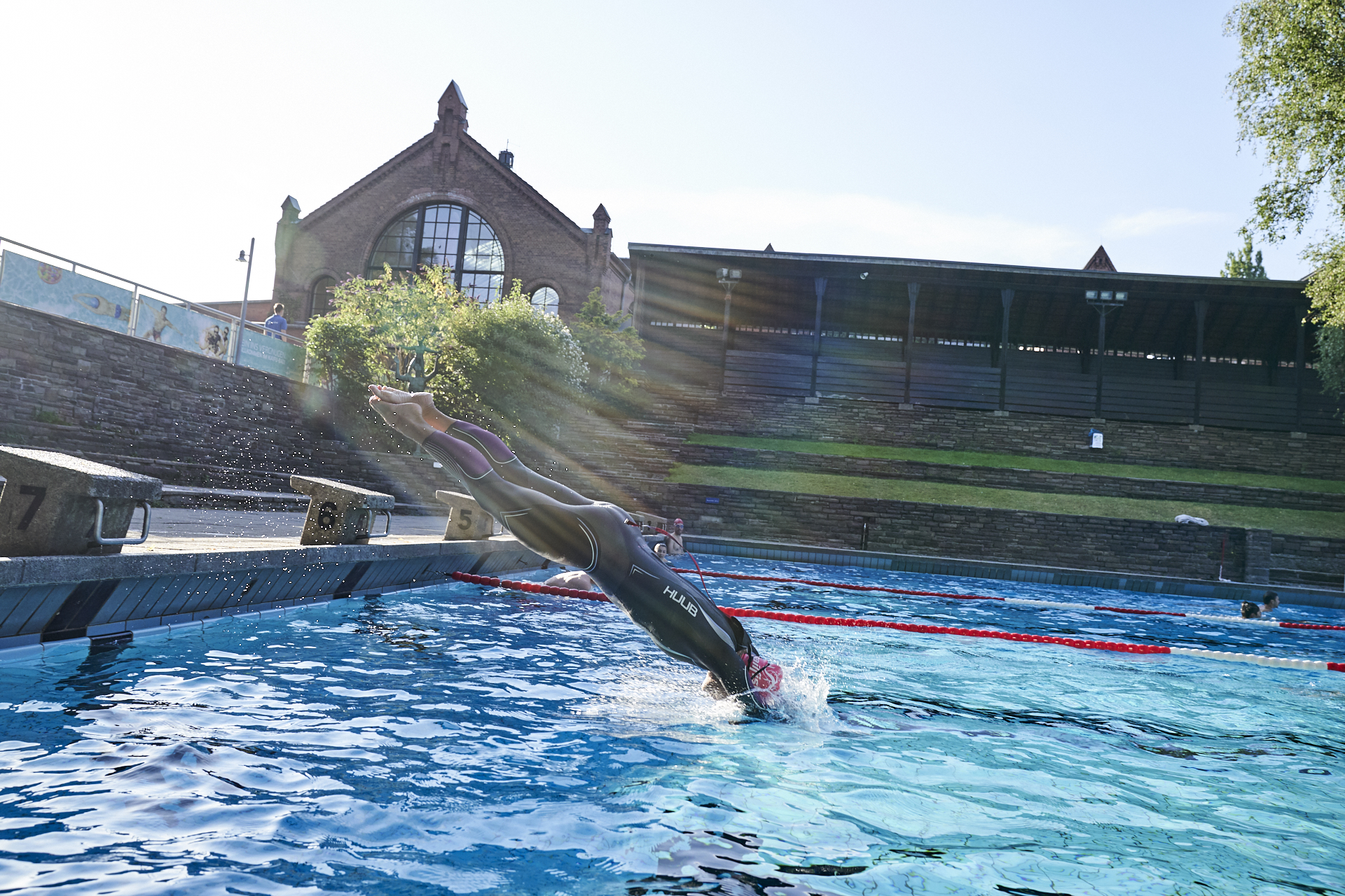 swimmer jumps into the water from the edge of the pool in a gym