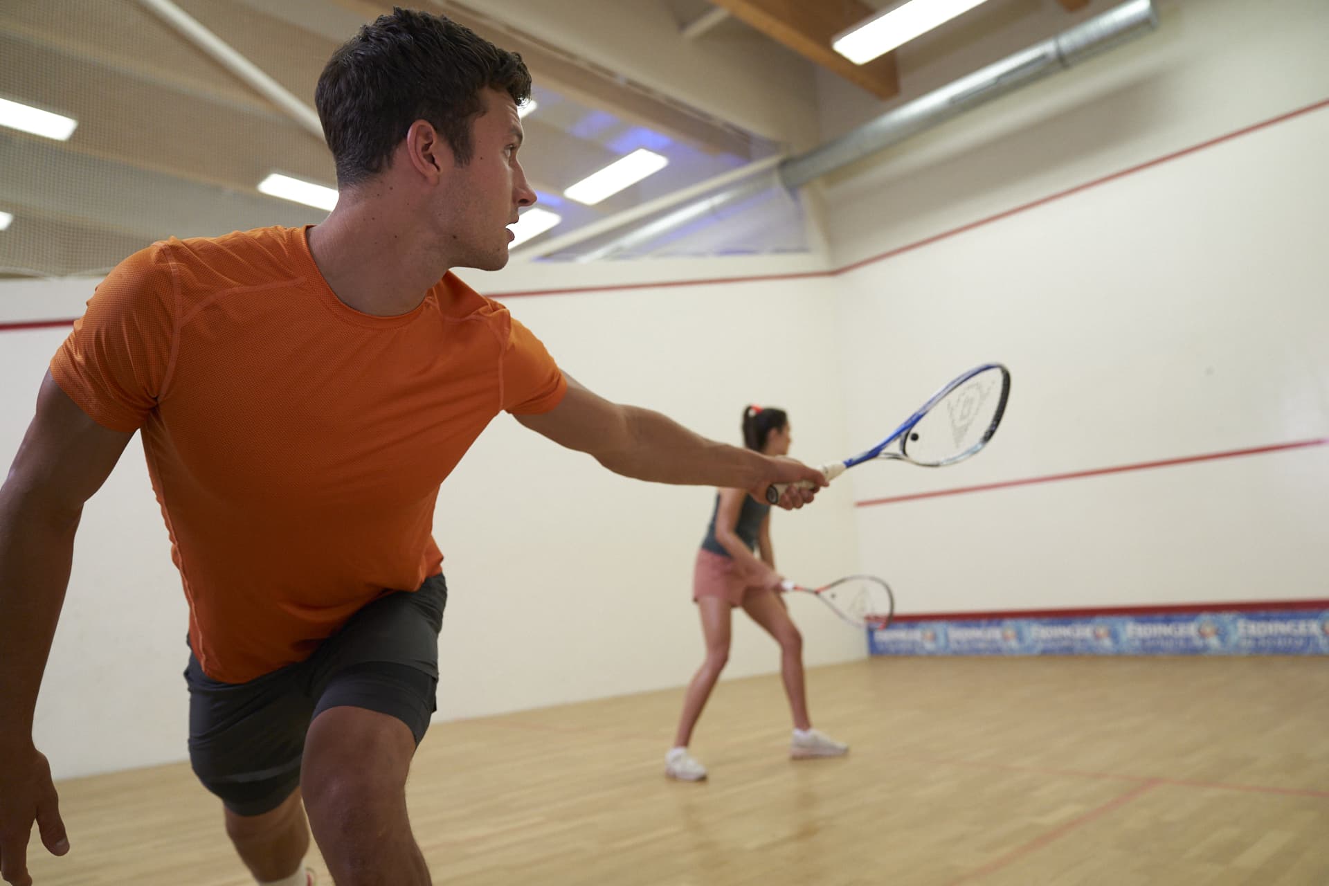 a man and a woman playing squash in the gym