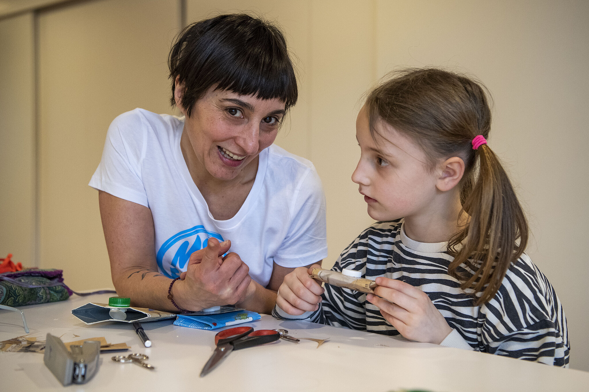 Eine Frau von der Kinderbetreuung bastelt mit einem Mädchen