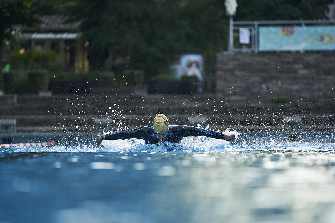 Ein Triathlet schwimmt im Neoprenanzug im Freibad